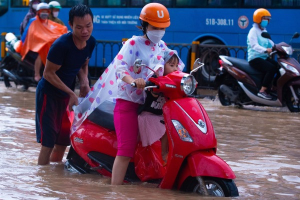 TP.HCM đổ mưa lớn, nước đục ngầu dâng ngang bánh xe