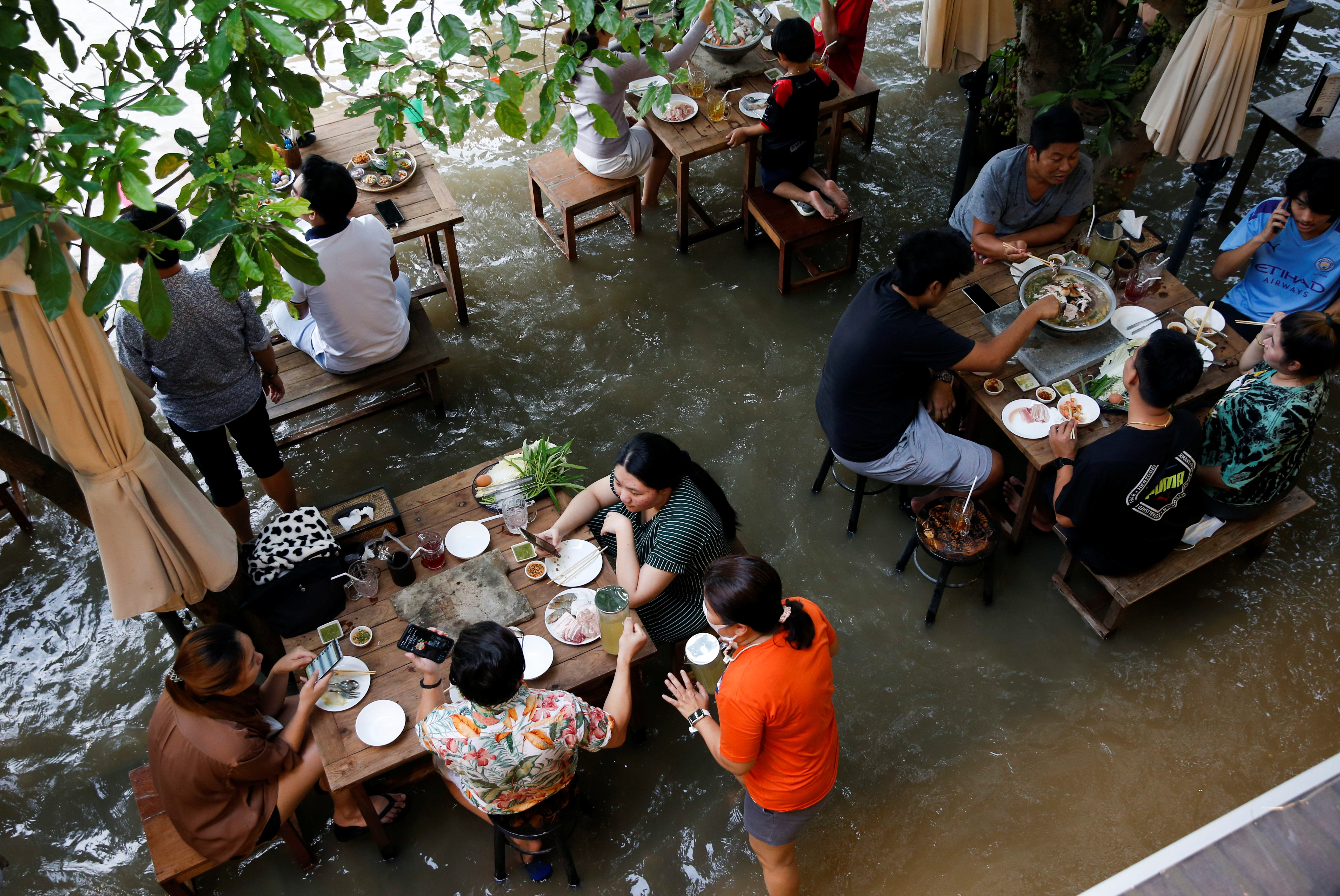 Khách ngồi 'nhậu' giữa biển nước lụt ở Thái Lan, vừa ăn vừa chơi với cá