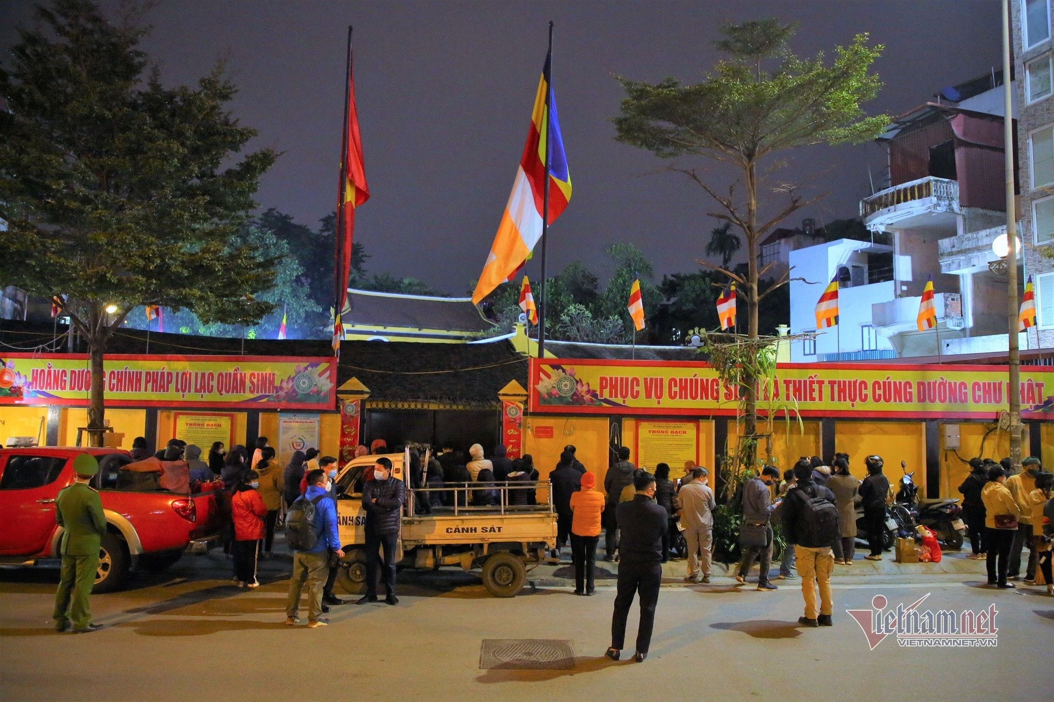 Người dân đứng ngoài cổng ngồi xe máy dự lễ cầu an online ở chùa phúc khánh