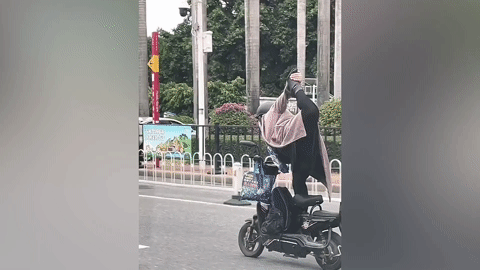 Người phụ nữ vừa lái xe máy điện vừa tranh thủ tập yoga