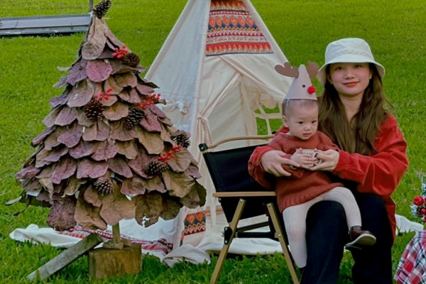 Mẹ trẻ nhặt lá bàng khô ở công viên làm cây thông Noel