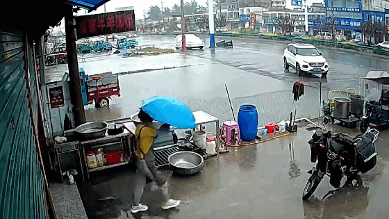 Nữ chủ quán lao ra giữa đường tặng ô cho cụ ông đang đi bộ dưới mưa