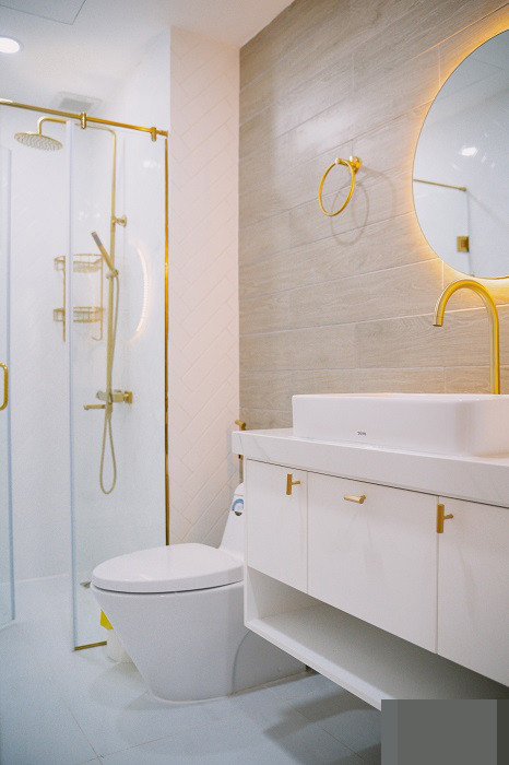 Phòng vệ sinh màu trắng nhã nhặn, các chi tiết mạ vàng nhấn nhá cho không gian thêm tinh tế, bớt đơn điệu.