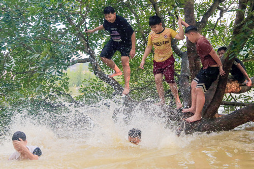 Trẻ em ngoại thành Hà Nội chơi đùa trong làn nước lũ