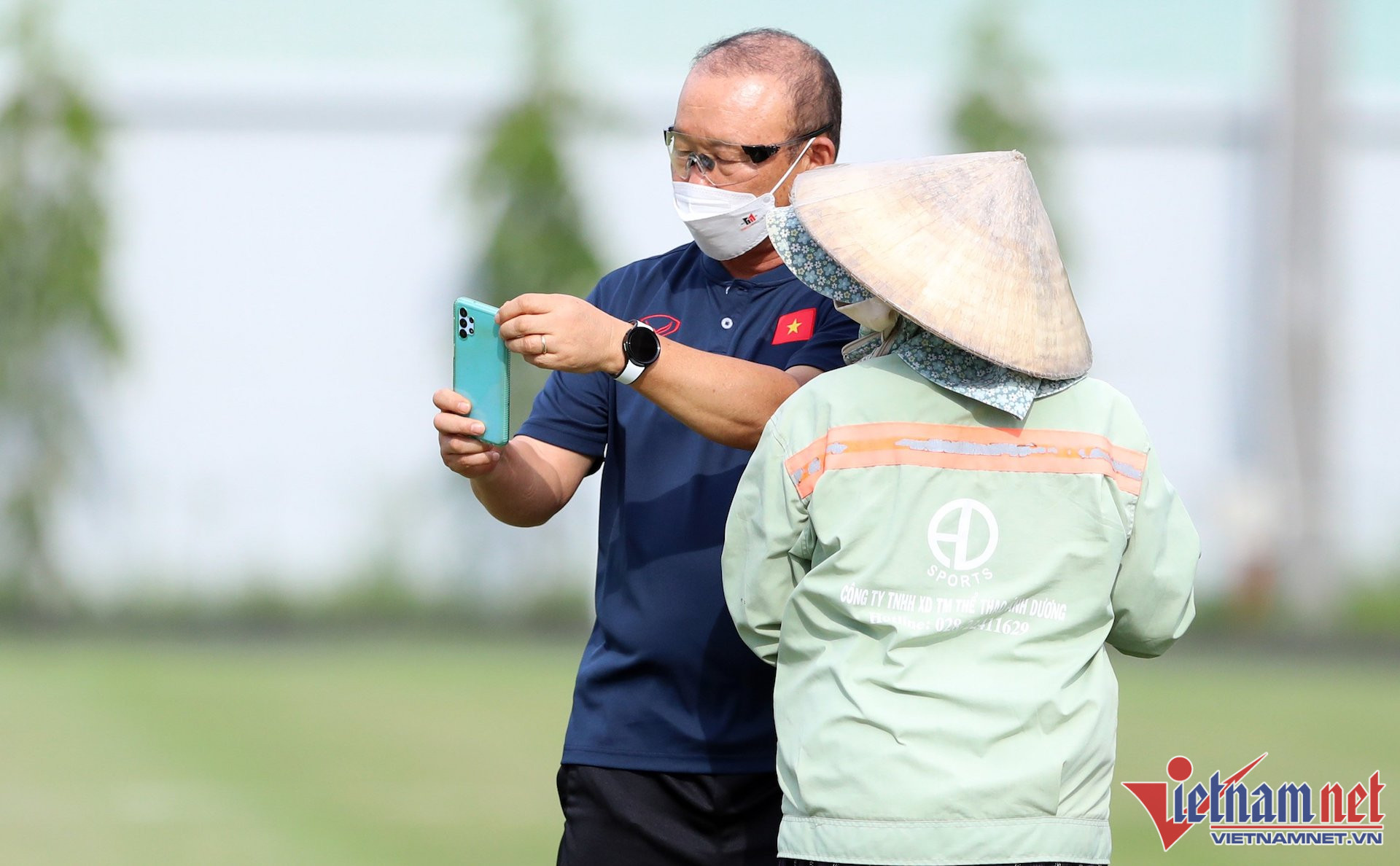 HLV Park Hang Seo dù khá âu lo cho việc có thể vắng Quang Hải tại AFF Cup 2022 nhưng vẫn vui vẻ chụp hình cùng một lao công dọn vệ sinh sân tập tuyển Việt Nam