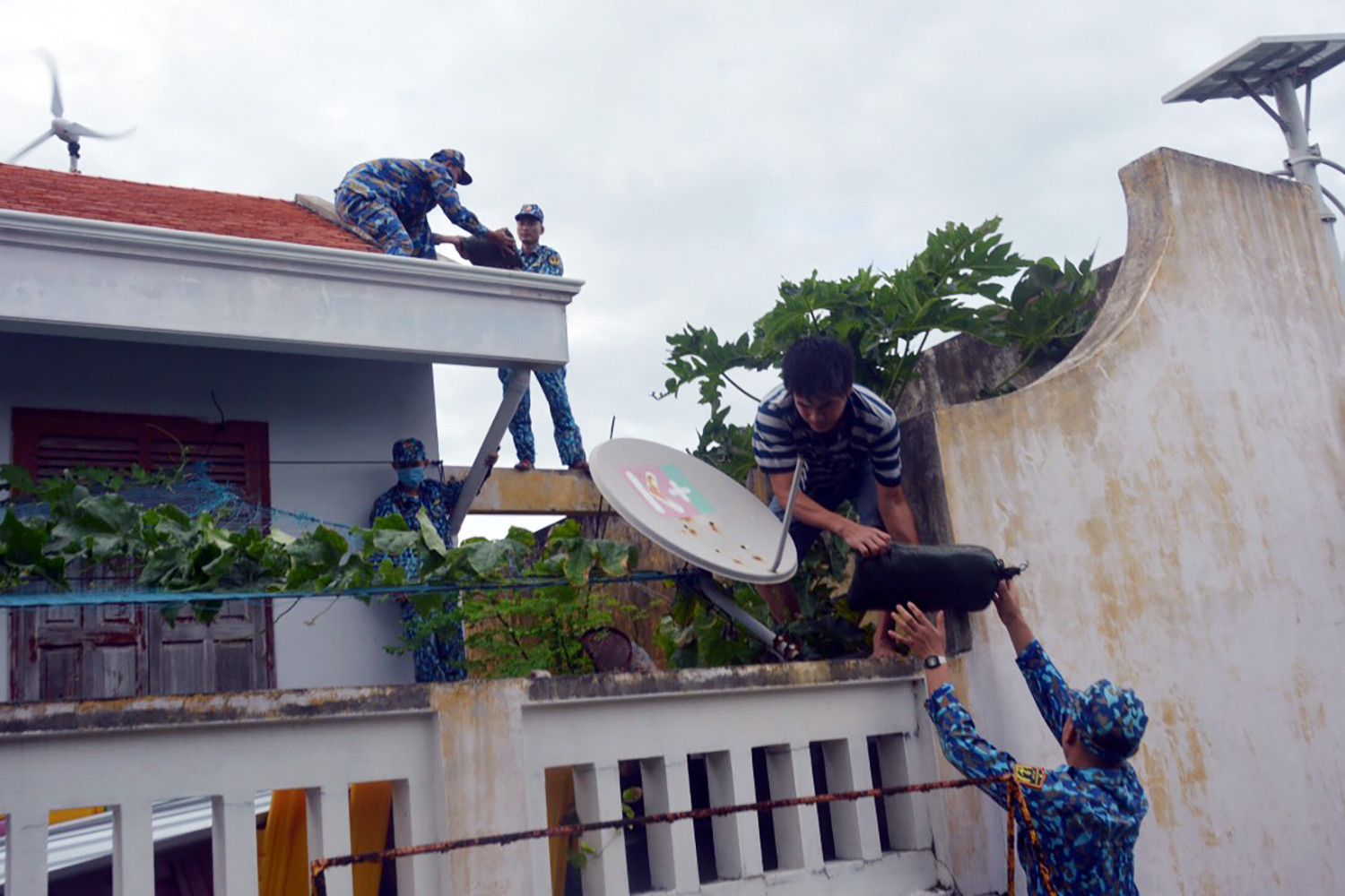 Chiến sĩ huyện đảo Trường Sa giúp dân chằng buộc mái nhà ứng phó bão Noru