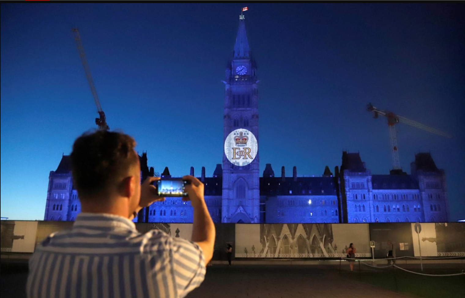 Người đàn ông chụp lại biểu tượng hoàng gia Anh được chiếu trên Tháp Hòa bình thuộc Tòa nhà Quốc hội ở Ottawa, Canada.