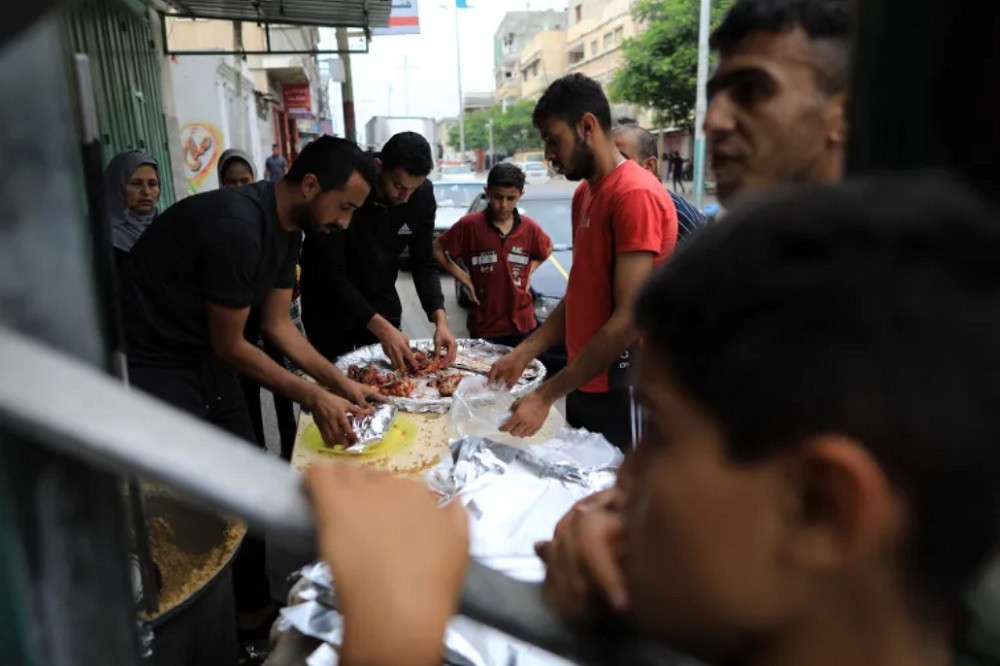 Abu Assi và người thân phát thức ăn cho nạn dân Dải Gaza. Ảnh: Al Jazeera