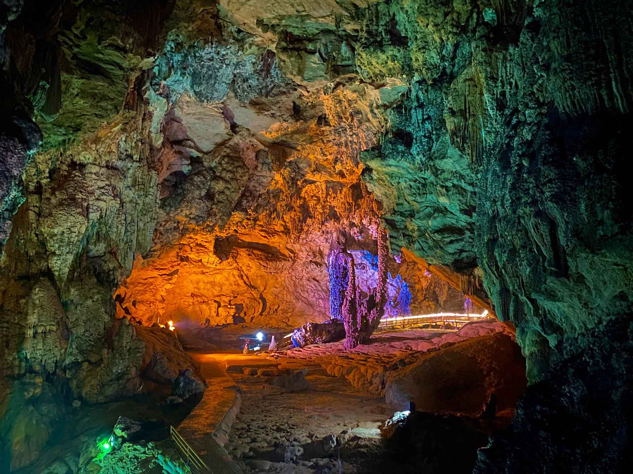Inside Nguom Ngao Cave with glowing stalactites and stalagmites illuminated by ambient lighting