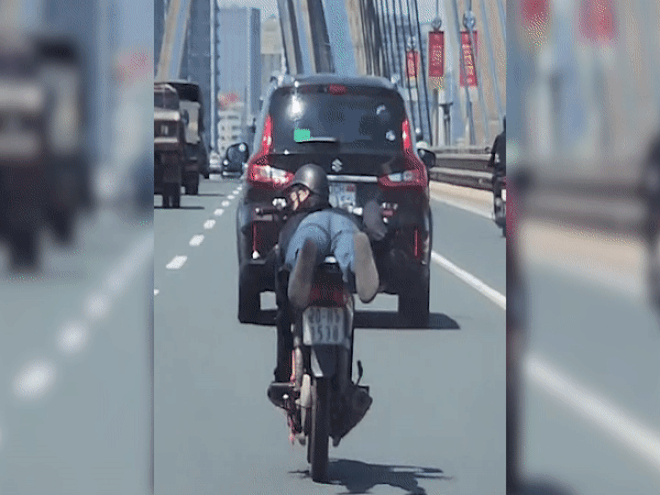 Nam thanh niên nằm trên yên xe máy phóng vun vút qua cầu Nhật Tân