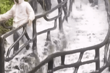 Du khách chống gậy xuống núi giữa mưa lũ như thác đổ ở Trung Quốc