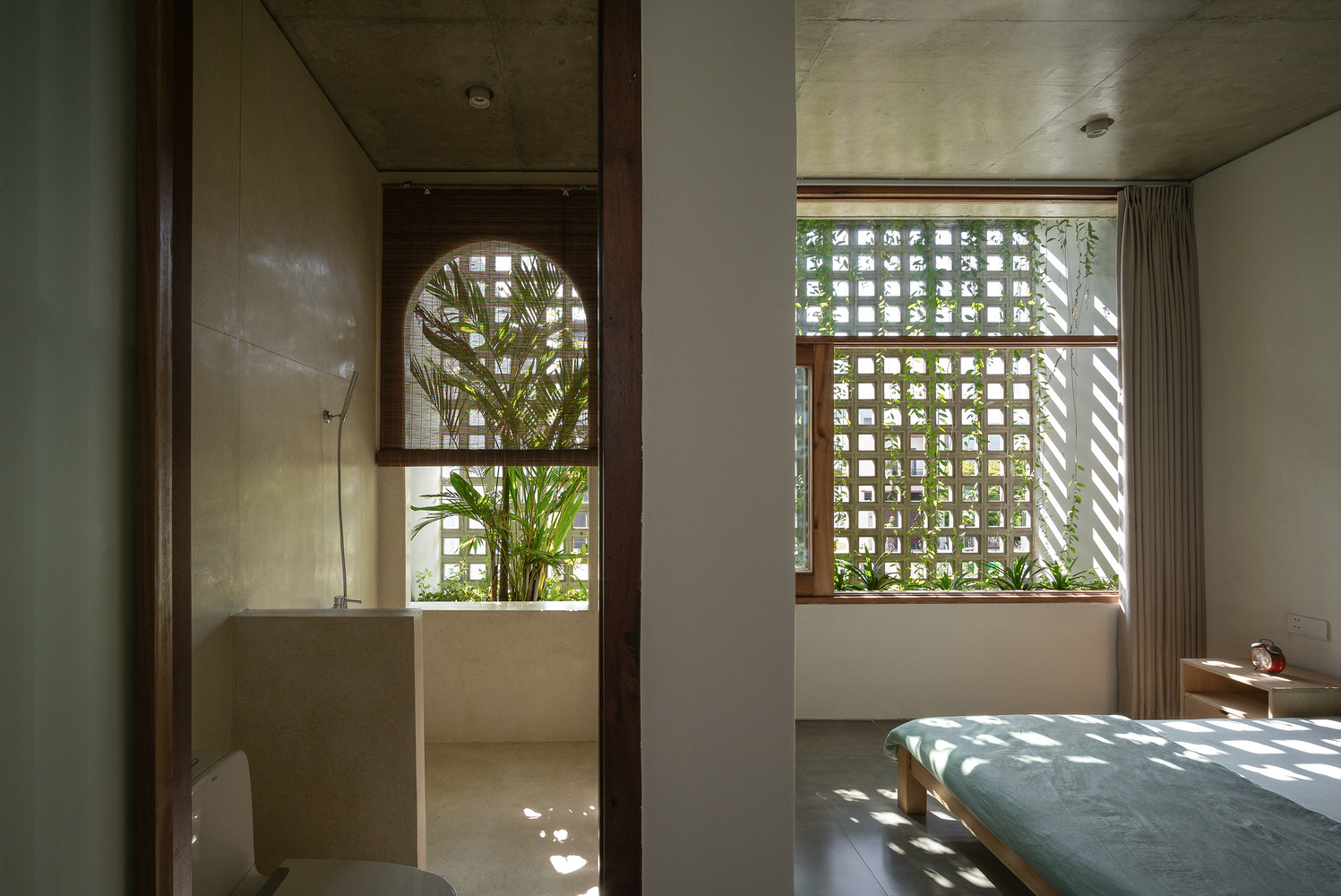 Cửa kính trong suốt, với thiết kế cây xanh kết hợp tường là các ô gạch thoáng phía sau nhà khiến phòng ngủ thực sự gần gũi với thiên nhiên.