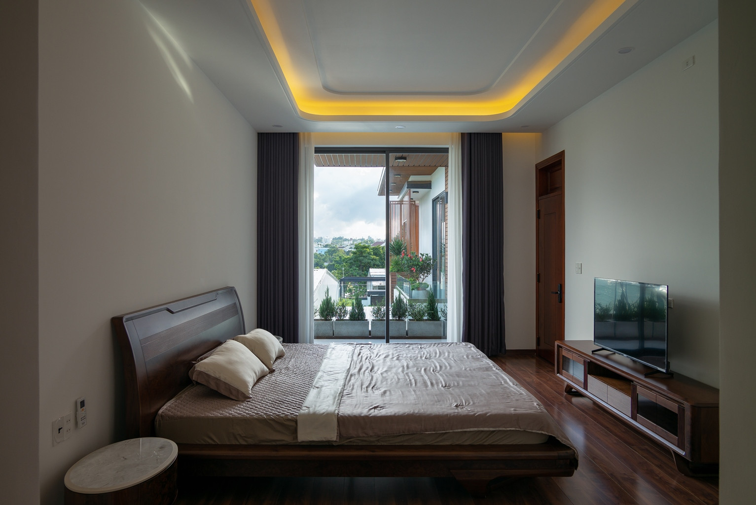 Phòng ngủ ở tầng 2 với thiết kế cửa kính tạo góc nhìn mở với bên ngoài, cảm giác thư thái với cây xanh, cảnh quan thiên nhiên.