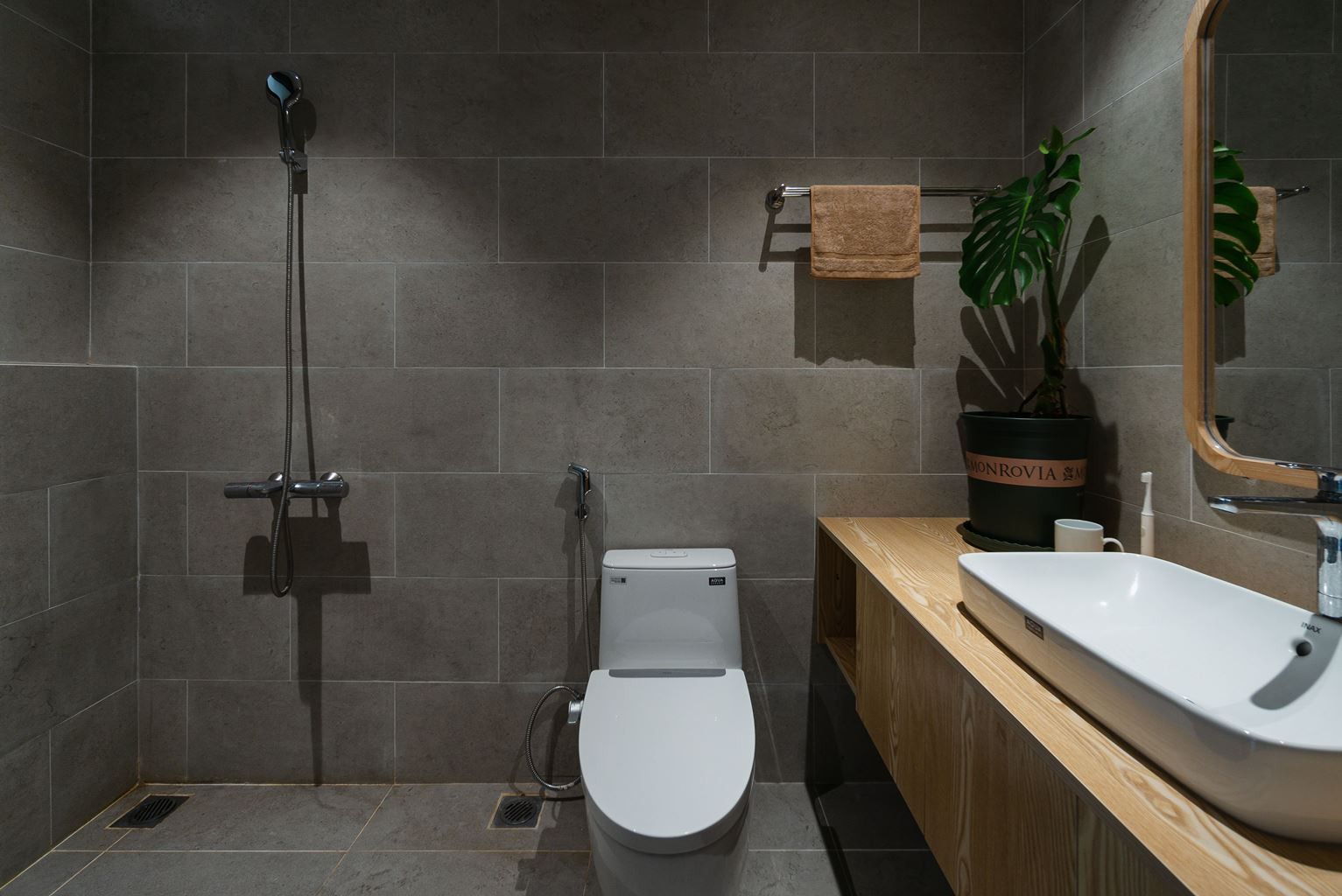 Khu vực vệ sinh được sử dụng gạch ốp màu xám, kết hợp tủ gỗ.