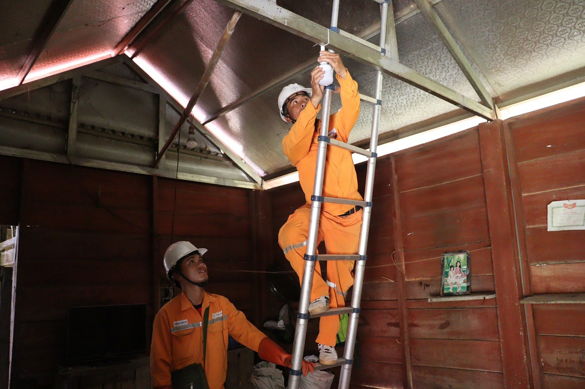 Công nhân Điện lực Quảng Bình lắp bóng điện trong nhà cho bà con.jpg