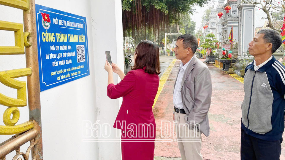 Du khách quét mã QR để tra cứu thông tin đã được số hóa về khu di tích lịch sử - văn hoá cấp quốc gia đền Xuân Bảng (Xuân Trường).