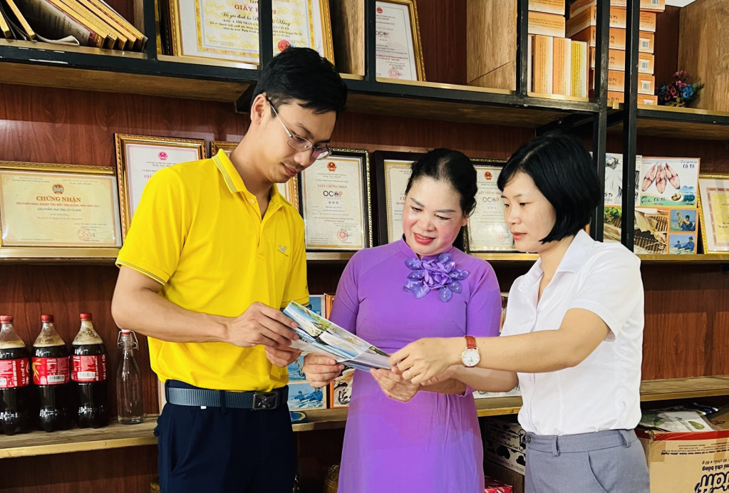 Cán bộ HND và nhân viên Bưu điện huyện Cô Tô hướng dẫn hộ kinh doanh đưa sản phẩm lên sàn thương mại điện tử. Ảnh: Ngọc Trâm