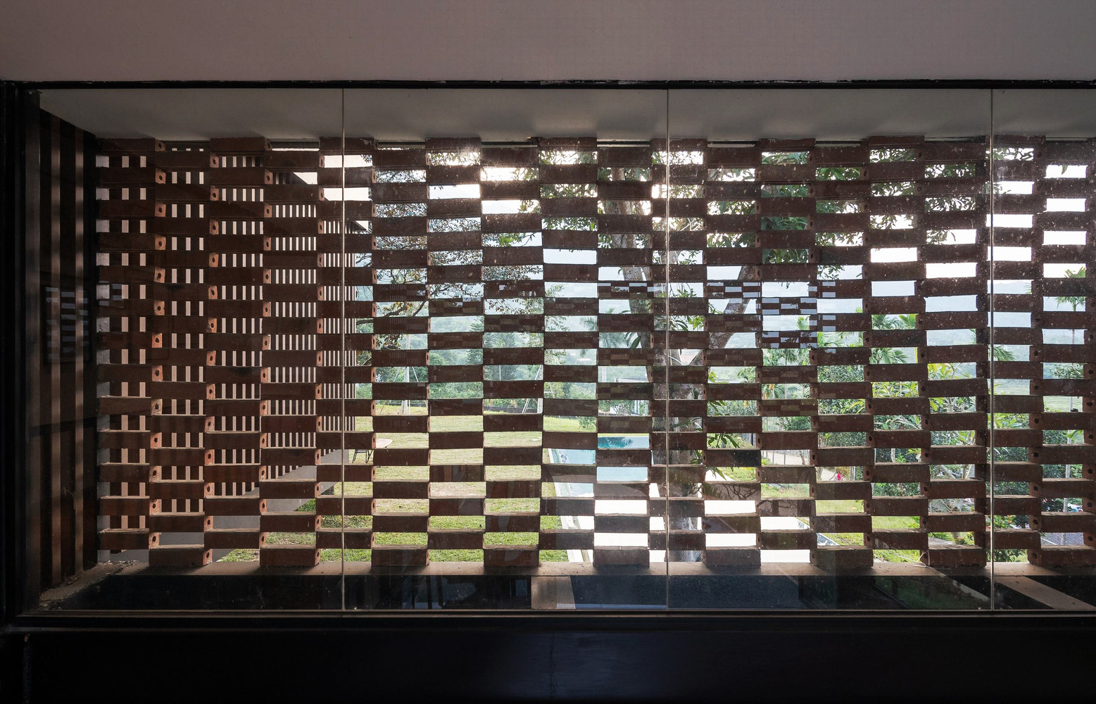 Để tránh nắng hướng Tây nhưng không mất tầm nhìn từ trong nhà, kiến trúc sư sử dụng rèm bằng gạch.