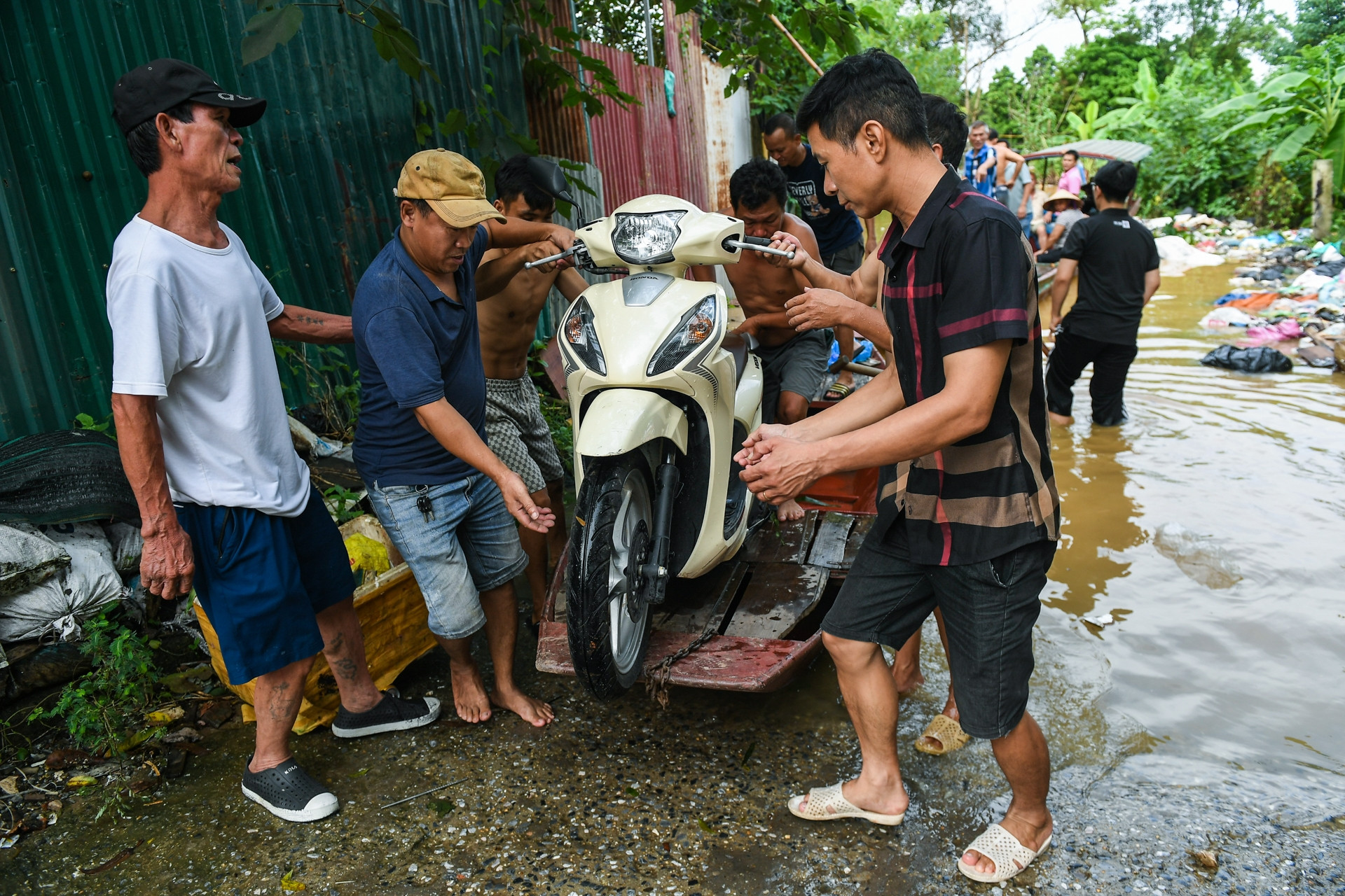 Nước sông Hồng tại Hà Nội dâng cao, người dân chèo thuyền đưa xe máy vào bờ