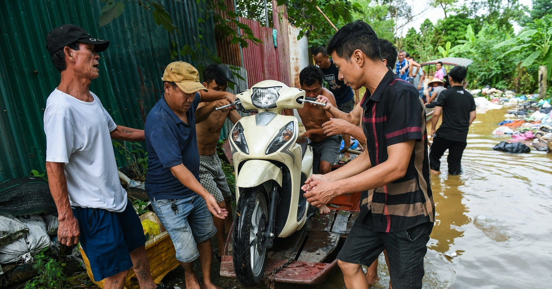 Nước sông Hồng tại Hà Nội dâng cao, người dân chèo thuyền đưa xe máy vào bờ