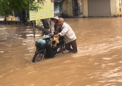 Xúc động cảnh ông lão Hà Nội đẩy xe giữa dòng nước ngập đưa vợ đi khám bệnh