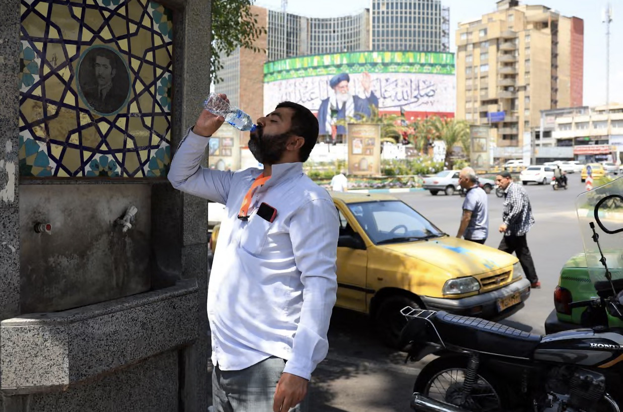 Một người Iran uống nước từ vòi công cộng giữa lúc trời nóng 40 độ. Ảnh: EPA