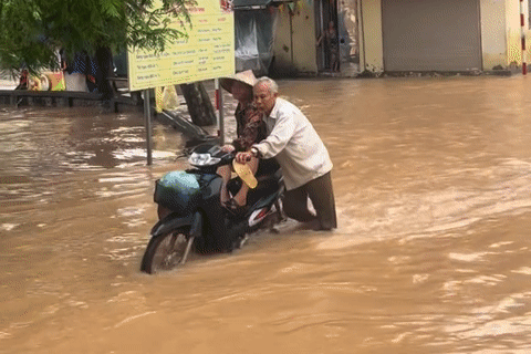 Xúc động cảnh ông lão Hà Nội đẩy xe giữa dòng nước ngập đưa vợ đi khám bệnh