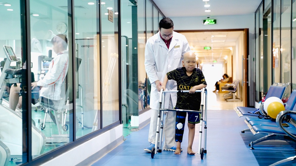 Hình ảnh bé Minh tập đi bằng dụng cụ hỗ trợ sau phẫu thuật.jpeg