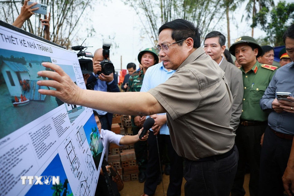Thủ tướng Phạm Minh Chính xem phương án xây dựng nhà tránh lũ cho bà con, nhân dân vùng lũ. (Ảnh: Dương Giang/TTXVN)