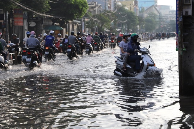 Người dân TPHCM xắn quần, co chân vượt đường ngập lênh láng vào giờ cao điểm
