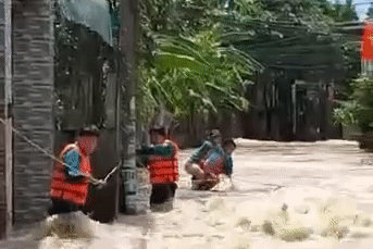 Khu dân cư bị ngập, dân quân cõng người phụ nữ qua dòng nước chảy xiết