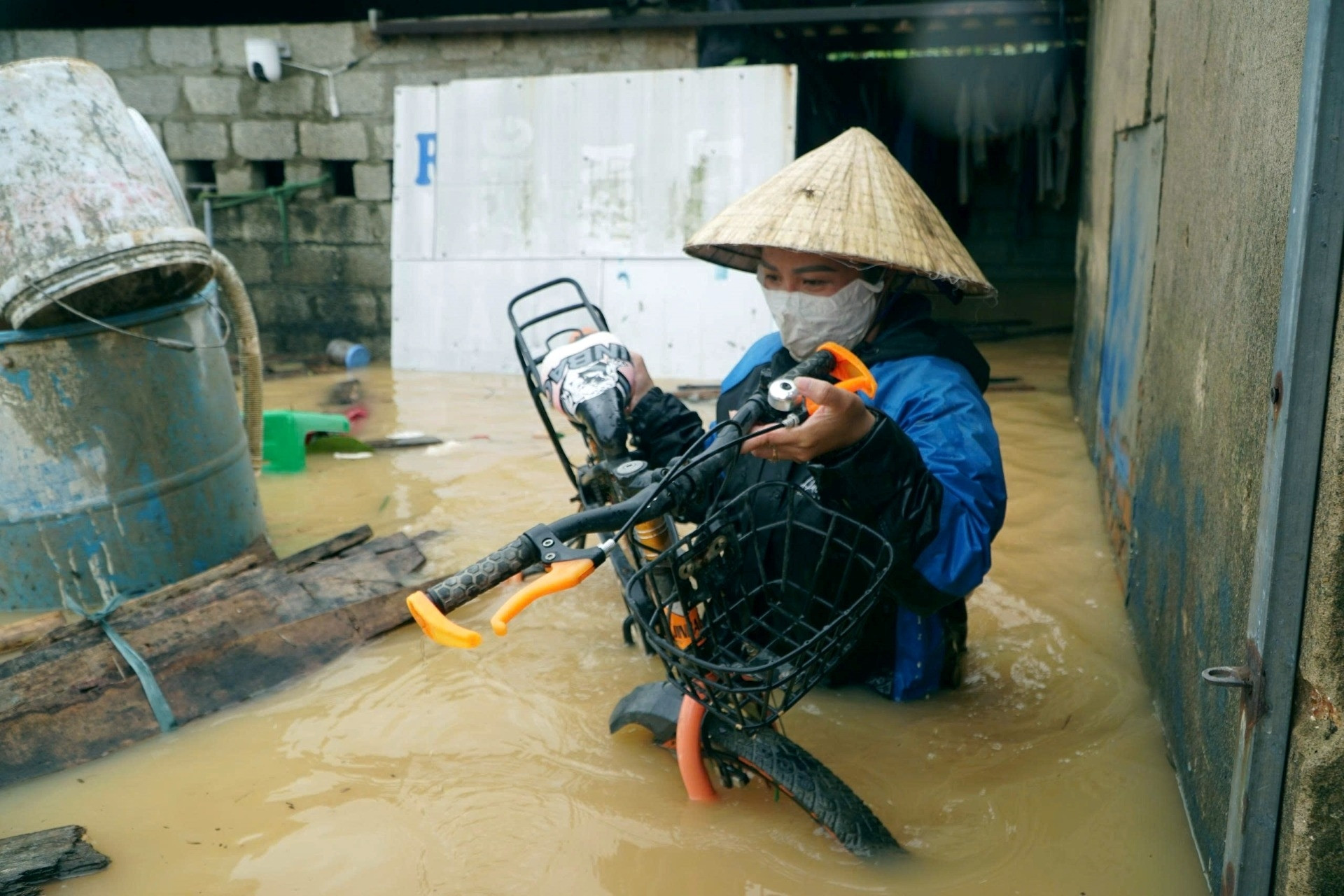 Người phụ nữ Thanh Hóa mò tìm xe đạp cho con trong nước lũ ngập quá nửa căn nhà