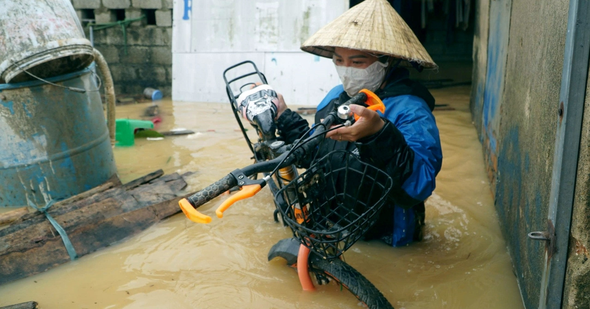 Người phụ nữ Thanh Hóa mò tìm xe đạp cho con trong nước lũ ngập quá nửa căn nhà
