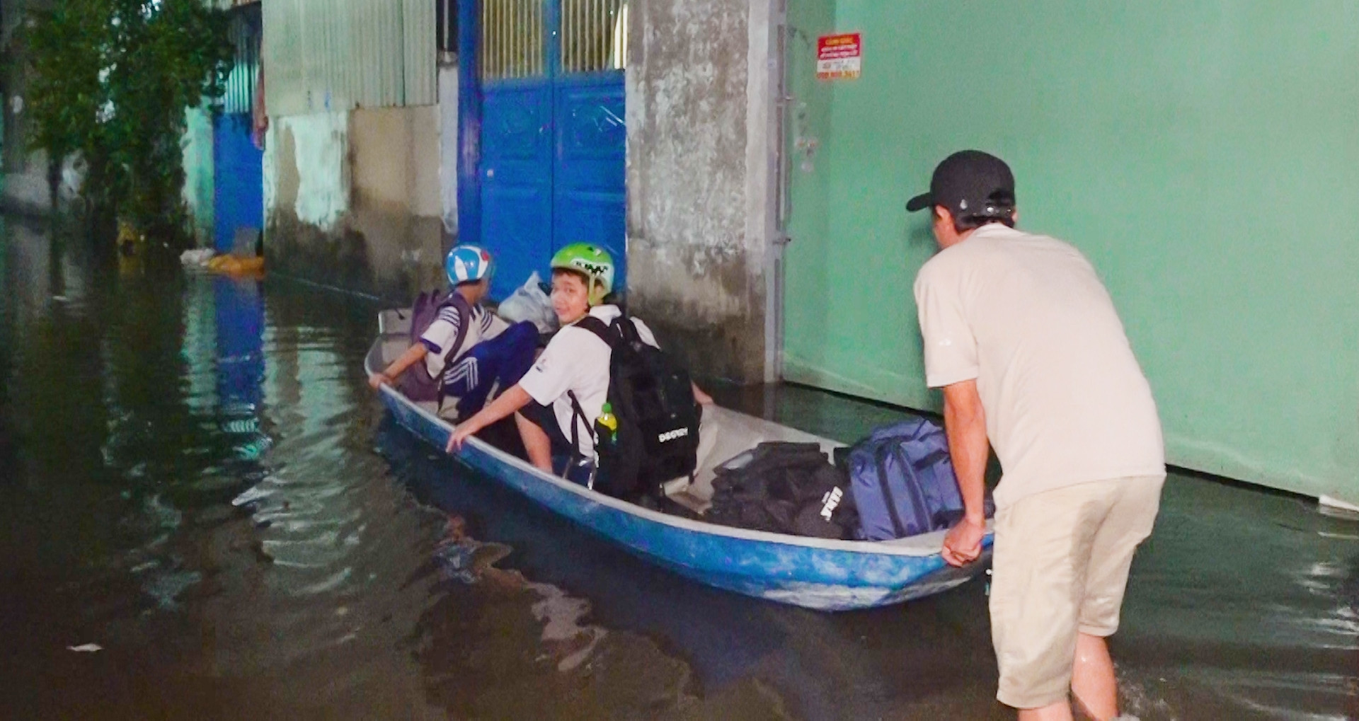 Mưa tạnh hơn một ngày, hẻm ở TPHCM vẫn ngập sâu, dân dùng thuyền đưa con đi học