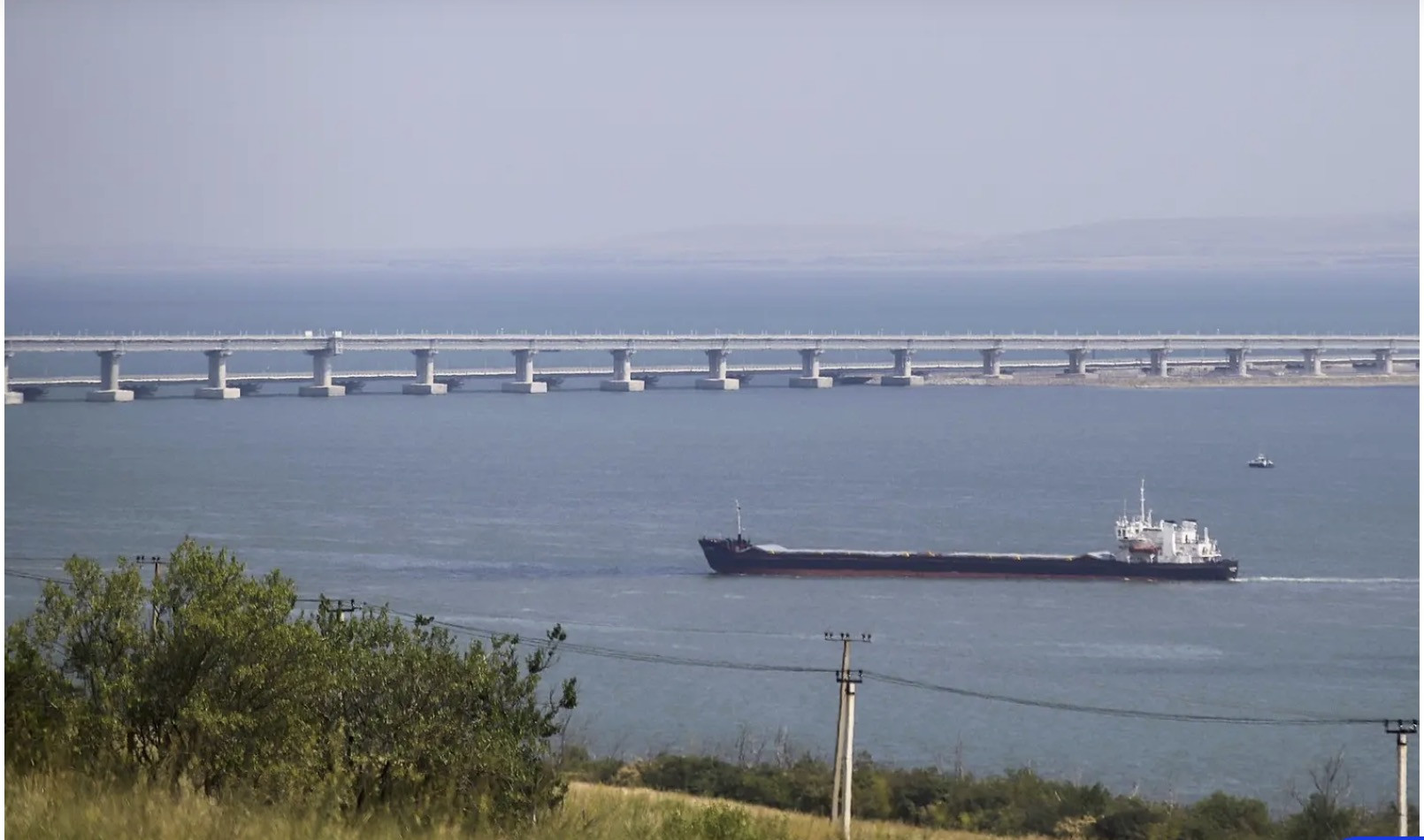 Tàu chở hàng đang băng qua eo biển Kerch với cầu Crưm ở phía sau. Ảnh: Anadolu