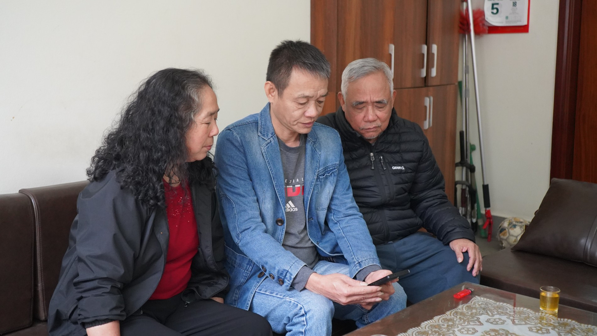 Ông Đỗ Danh Hoan (áo đen), ông Nguyễn Thái Dương (áo xanh) cùng gia đình xem lại thước phim Trung tá Lao Hoàng Hải và đồng đội dẫn đường cho xe chở bệnh nhân đi .jpg