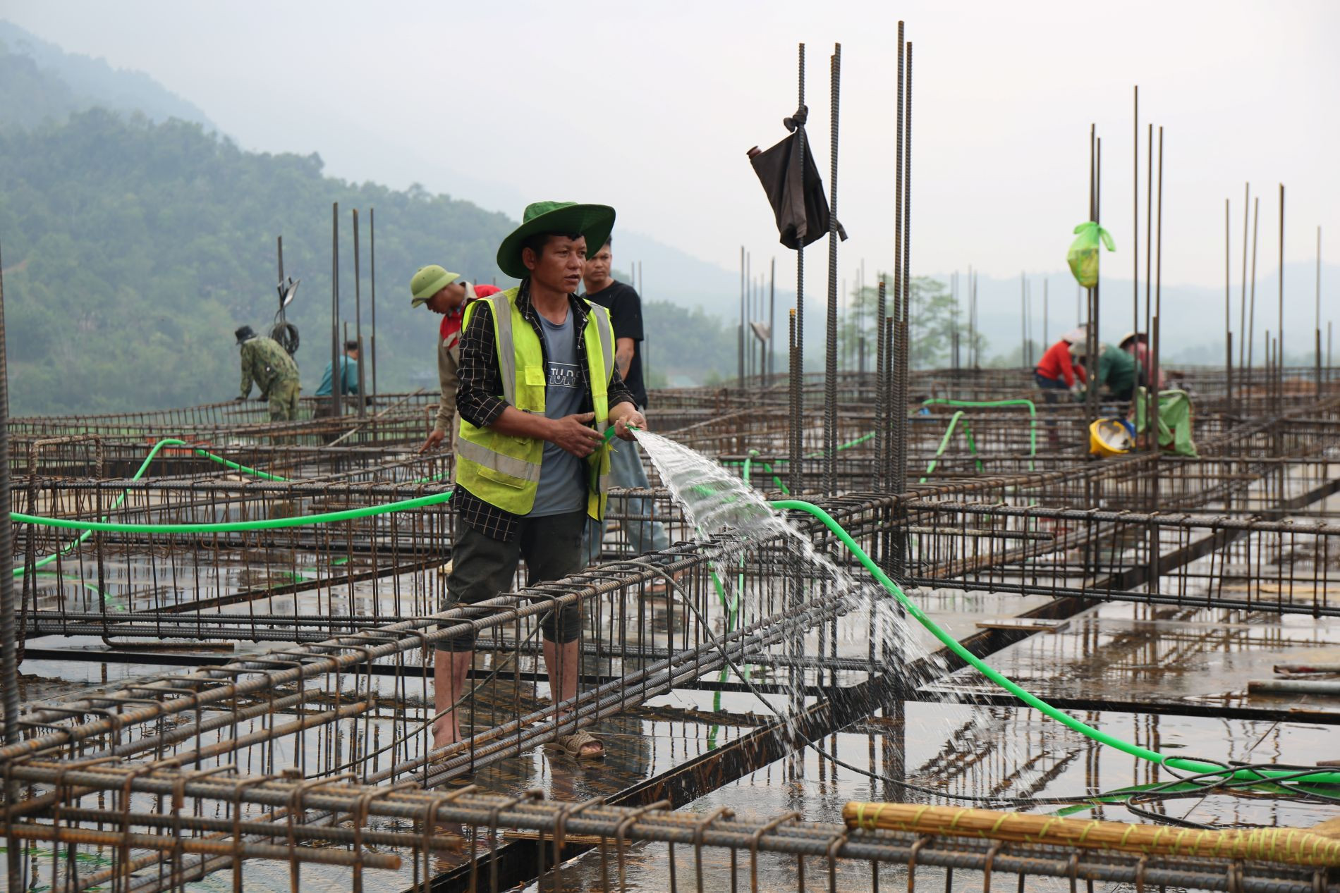 Các công nhân tưới nước chuẩn bị đổ sàn tại công trình trường nội trú liên cấp xã Tri Lễ - Ảnh: T.H