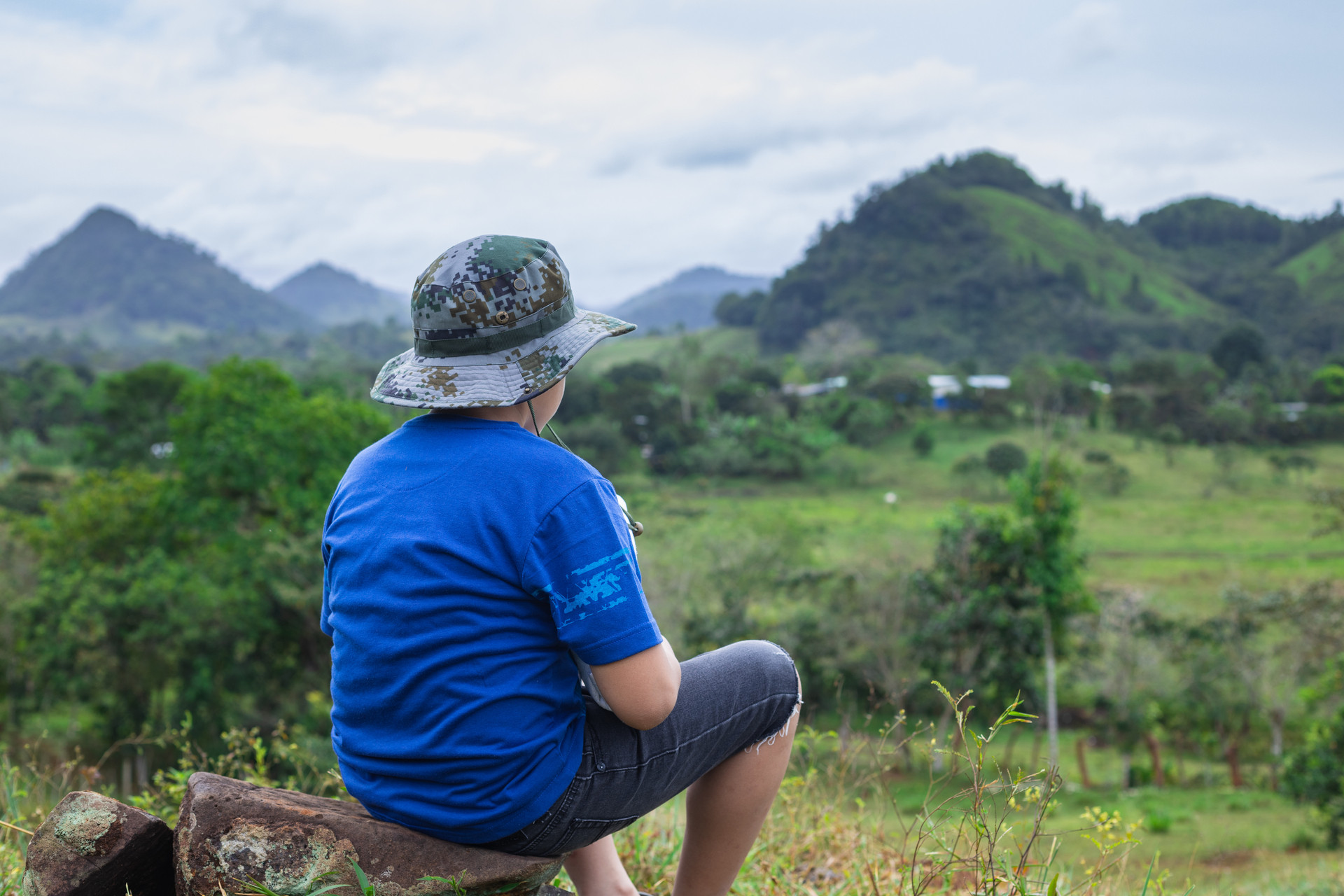 closeup shot child sitting stone with view hills mountains (1).jpg