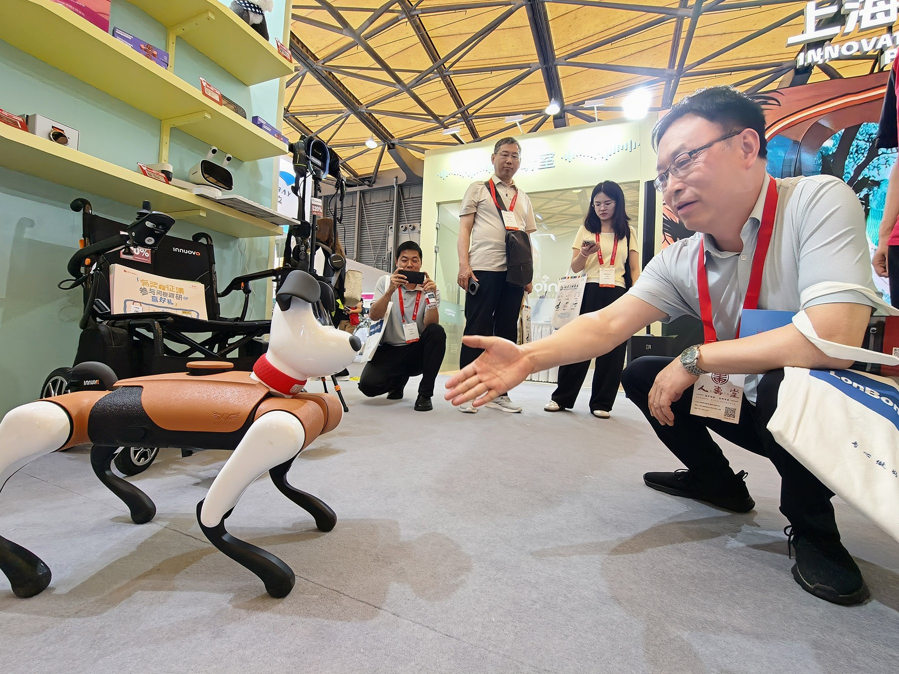 Khách tham quan tương tác với một chú chó robot trong Triển lãm Quốc tế về Chăm sóc Người cao tuổi, Y học Phục hồi chức năng và Chăm sóc sức khỏe Thượng Hải 2026. (LIU XIN / FOR CHINA DAILY)