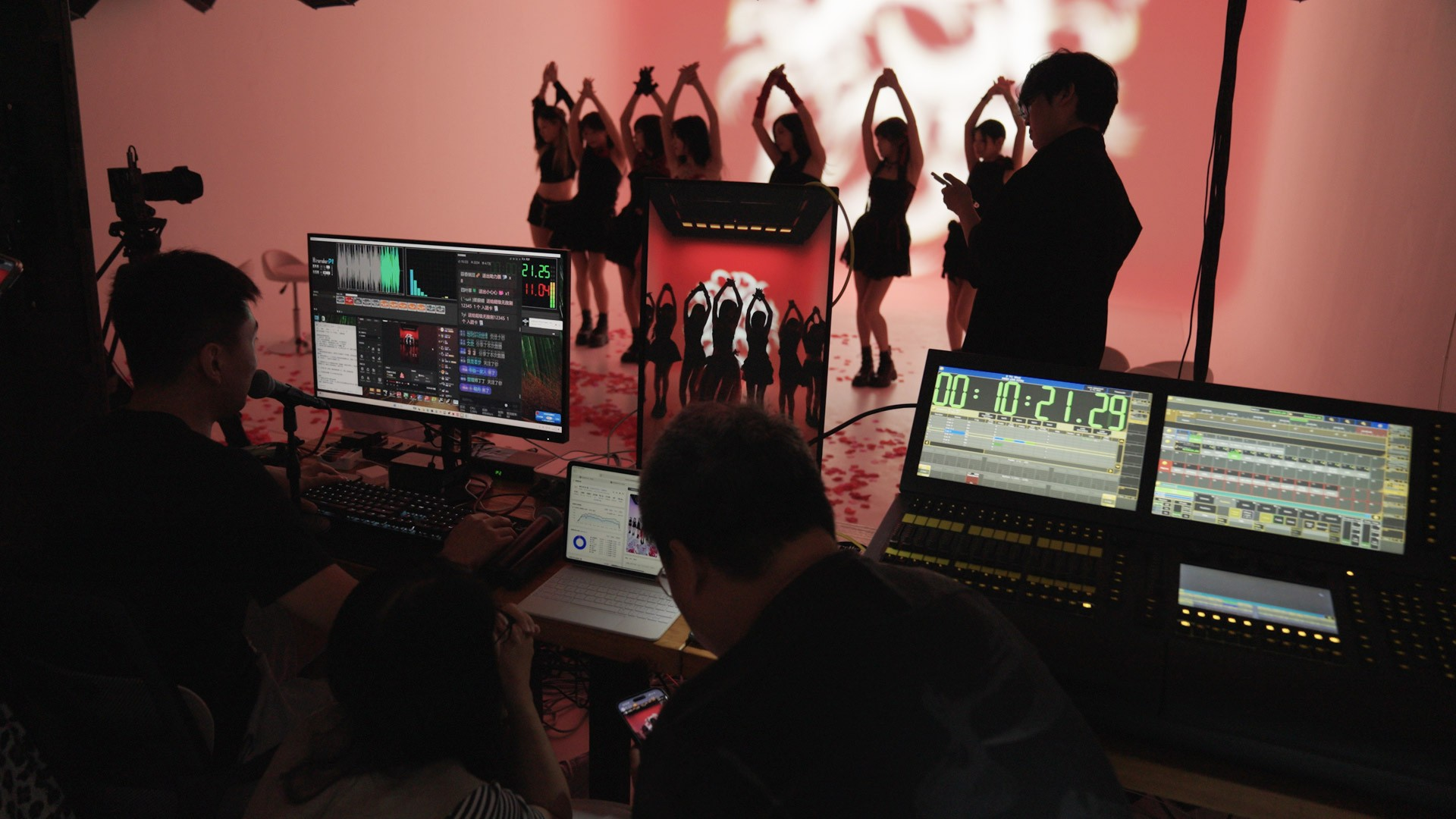 Performers dance as backstage staff monitor live data and video feeds in Chongqing, September 2025. Lü Xiao/Sixth Tone