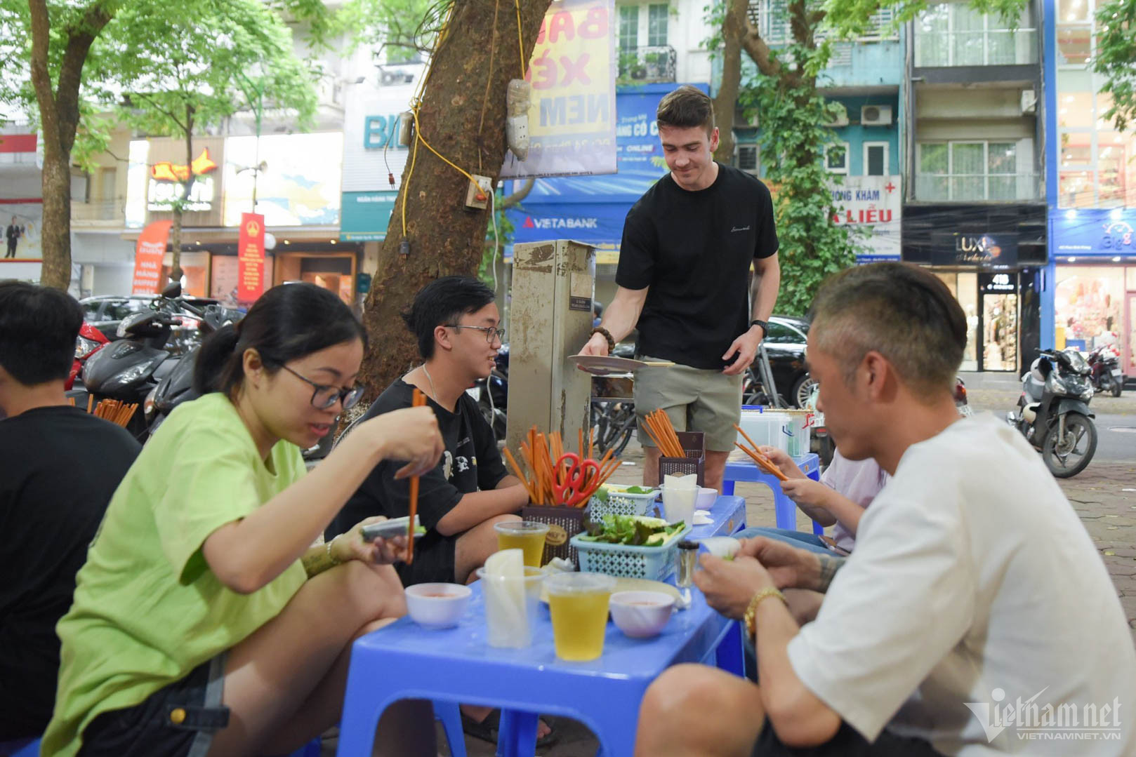 Foreign man grills nem lui, sells banh xeo at pavement shop in Hanoi