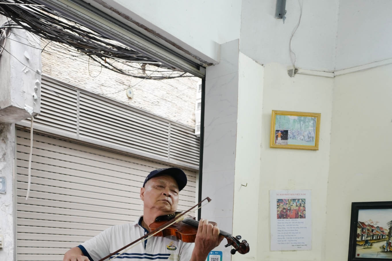 Owner plays the violin while patrons dine at humble Hanoi snail-eatery