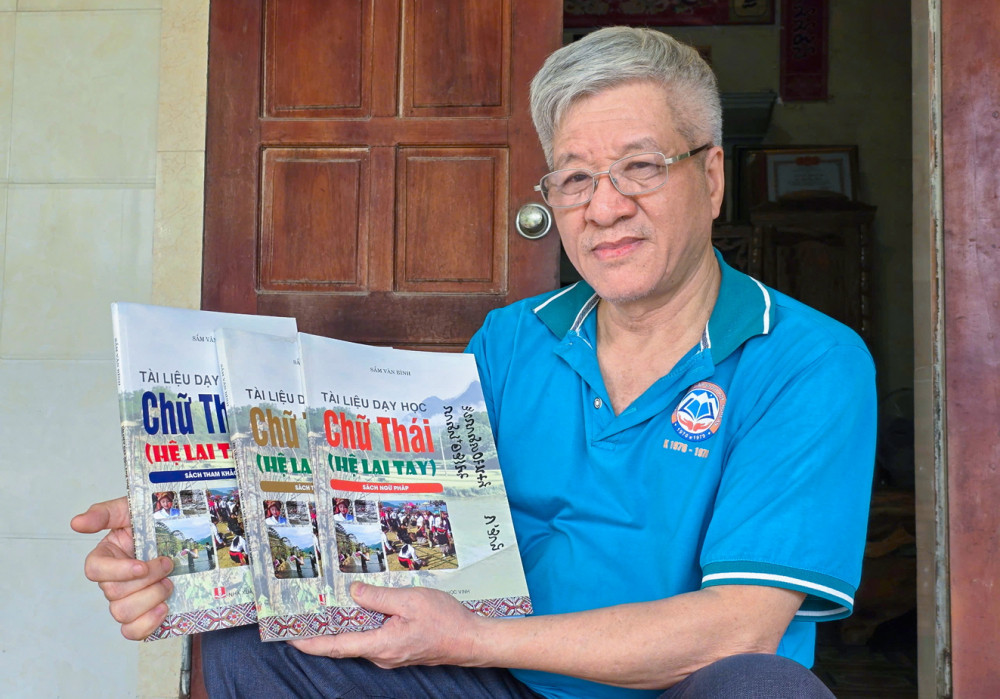 Ông Sầm Văn Bình bên bộ sách dạy học chữ Thái hệ Lai Tay