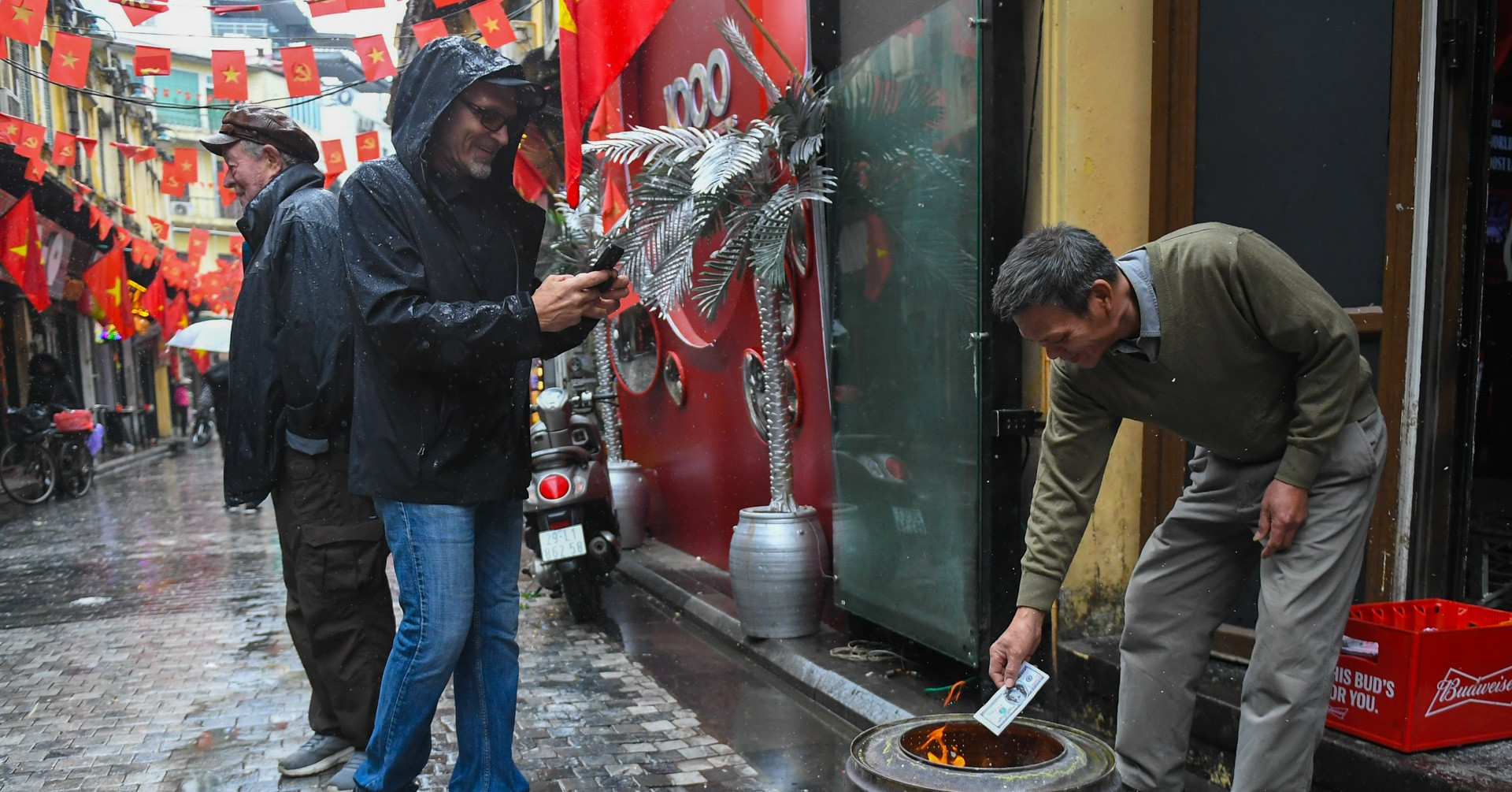 Hanoians burn offerings early for Kitchen Gods as tourists stop to watch