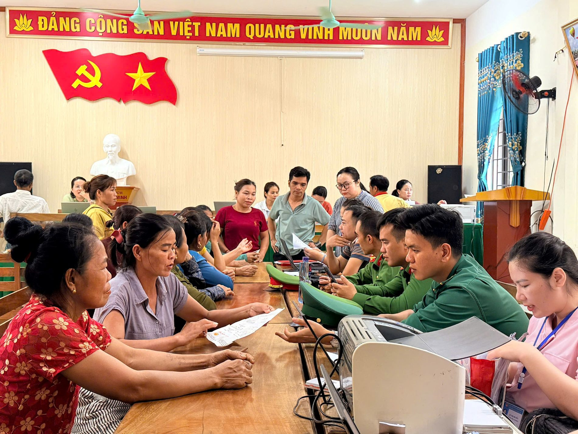 Các lực lượng Công an xã, Bộ đội Biên phòng hỗ trợ người dân cài đặt, sử dụng ứng dụng VNeID, hướng dẫn nộp hồ sơ trực tuyến và thanh toán không dùng tiền mặt - Ảnh: B.D